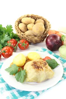 Stuffed cabbage with potatoes and tomato on a light background