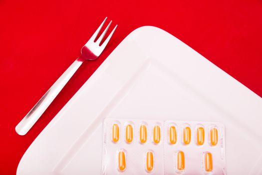 A white plate with medicine on red background.
