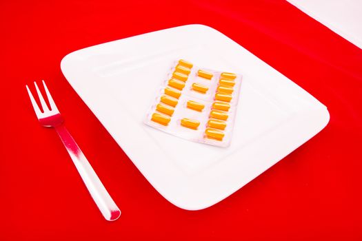 A white plate with medicine on red background.
