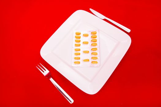 A white plate with medicine on red background.
