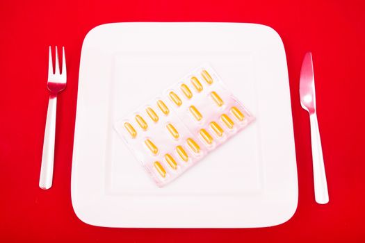 A white plate with medicine on red background.
