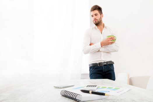 A young adult man at home drinking coffee.
