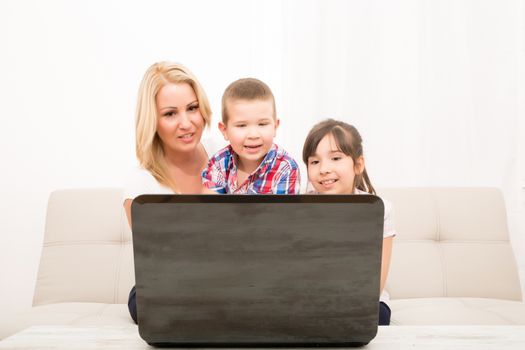 A mother using with her son and daughter a laptop computer.