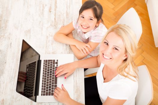 A mother with her daughter looking at a Laptop at home.
