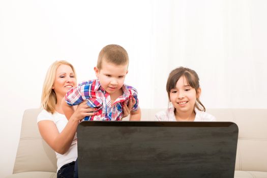 A mother using with her son and daughter a laptop computer.
