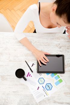 A young adult woman developing a business plan with her tablet PC at home.
