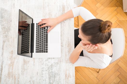 A young adult woman working on a laptop.