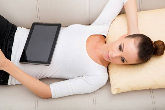 A young woman with a tablet pc on the sofa.
