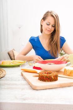 A young adult woman preparing a european style breakfast.
