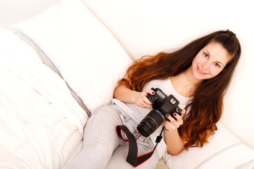 A young hispanic girl with DSLR camera in the bed. 
