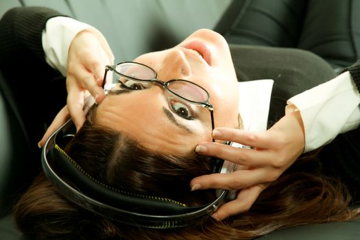 A girl listening to Music with headphones on the sofa.