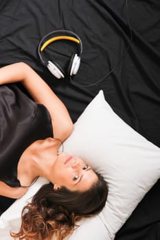 A young girl laying in bed, smiling with headsets
