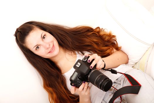 A young hispanic girl with DSLR camera in the bed. 
