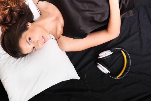 A young girl laying in bed, smiling with headsets

