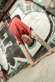 A performing hip-hop dancer in front of a graffiti wall.
