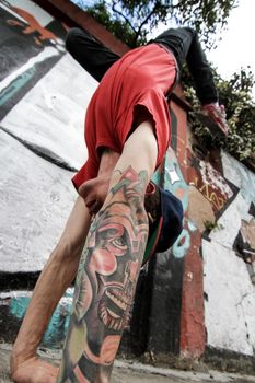 A performing hip-hop dancer in front of a graffiti wall.
