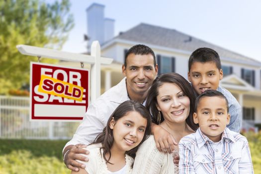 Happy Hispanic Family in Front of Their New House and Sold Home For Sale Real Estate Sign.
