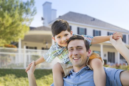 Mixed Race Father and Son Playing Piggyback in Front of Their House.