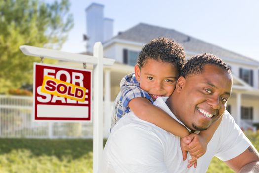 African American Father and Mixed Race Son In Front of Sold Home For Sale Real Estate Sign and New House.