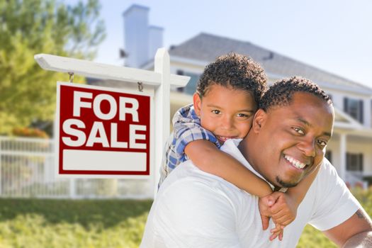 African American Father and Mixed Race Son In Front of Home For Sale Real Estate Sign and New House.