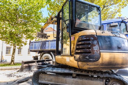 Excavator loading dumper truck with sand at construction site.
