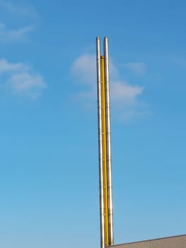 Chimney, flue pipe of a factory against a blue sky
