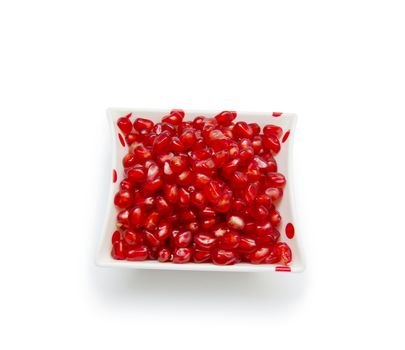 Loose pomegranate seeds in a white bowl