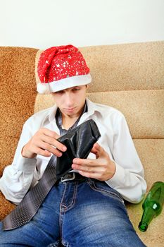 Teenager in Santa Hat Checking Empty Wallet on the Sofa at the Home