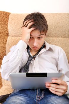 Troubled Teenager with Tablet Computer on the Sofa at the Home