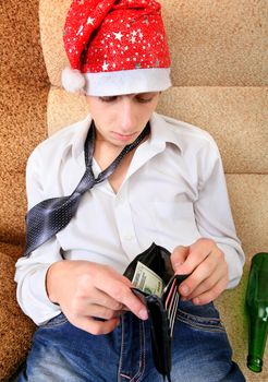 Teenager in Santa Hat Checking the Wallet on the Sofa at the Home