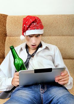 Shocked Teenager in Santa Hat with Tablet Computer and Bottle of the Beer