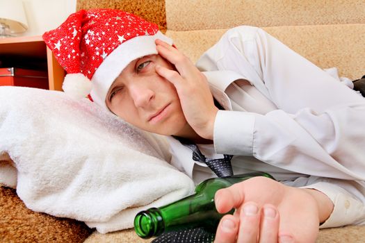 Sad and Tired Teenager with Bottle of the Beer and Santa Hat on the Sofa at the Home