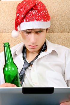 Troubled Teenager in Santa Hat with Tablet Computer and Bottle of the Beer