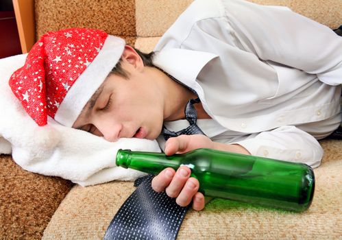 Drunken Teenager sleeping in Santa Hat and Bottle of the Beer on the Sofa