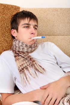 Sick Teenager with Thermometer on the Sofa at the Home