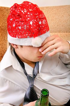 Sad and Tired Teenager with Bottle of the Beer and Santa Hat on the Sofa at the Home