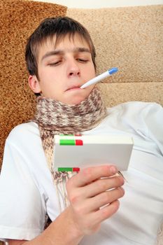 Sick Teenager with Thermometer and Drug on the Sofa at the Home