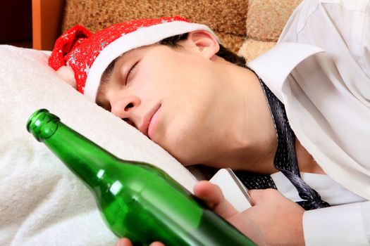 Teenager sleeping in Santa Hat and Bottle of the Beer on the Sofa