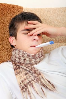 Sick Teenager with Thermometer on the Sofa at the Home