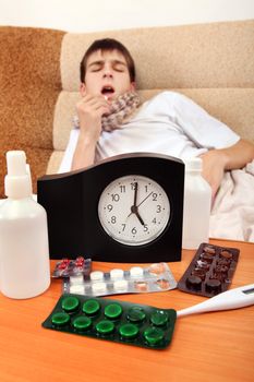 Focus on the Clock. Sick Teenager taking a Pill on the Bed at the Home