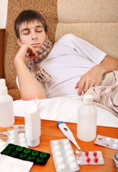 Sad and Sick Teenager on the Sofa at the Home with Pills on foreground