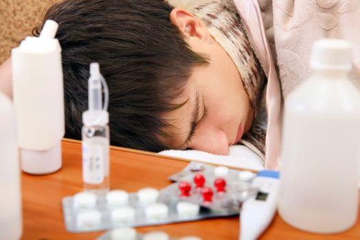 Sick Teenager sleeping on the Sofa with Pills on foreground