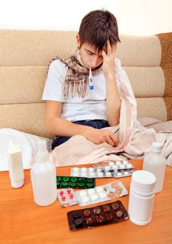 Sick Teenager on the Sofa at the Home with Pills on foreground