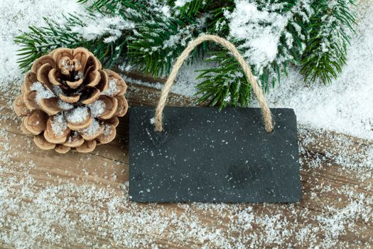 Black board of slate on old rustic wooden background, with snow