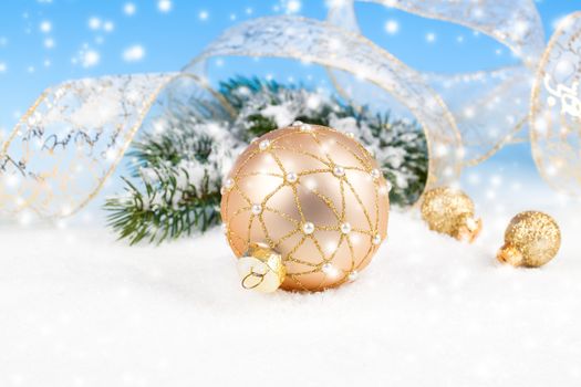 Christmas balls with ribbon on snow, on blue background