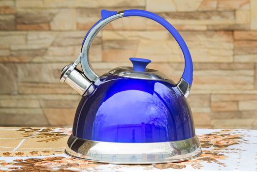 Beautiful and comfortable bright blue kettle with a signal of boiling water in the form of a whistle. Presented at the tablecloth table.