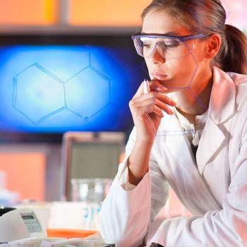 Portrait of a confident female health care professional in his working environment reviewing structural chemical formula written on a glass board.