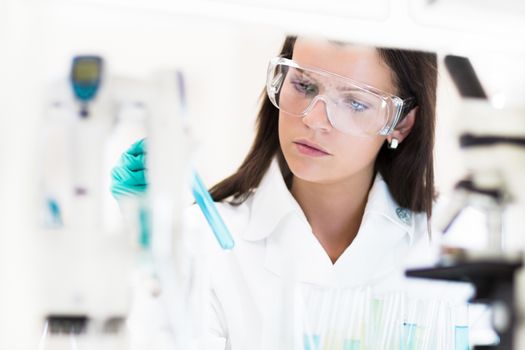 Attractive young PhD student scientist looking at the microscope slide in the life science research laboratory (biochemistry, genetics, forensics, microbiology ..)