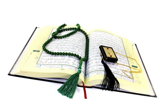 whipped Quran with rosary before light background