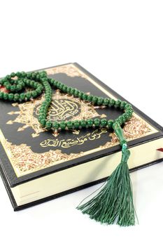 Quran with rosary before light background